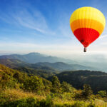 Šťastná rodina držiaca poukaz na let balónom s balónom v pozadí.