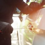Poškodené auto s preliačinou a škrabancami po vandalizme na parkovisku.