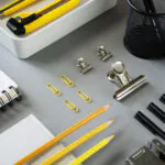 Kancelársky stôl s ekologickými pomôckami z recyklovaných materiálov a rastlinou v kvetináči.