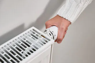 Žena nastavuje termostatickú hlavicu na radiátore